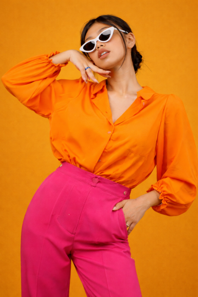 Confident woman wearing a bold monochrome outfit in hot pink or tangerine, styled head-to-toe in one bright color for a high-fashion spring look.