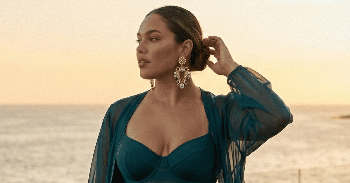 Plus size woman in a structured jewel-tone one-piece swimsuit layered with a sheer cover-up at a luxury infinity pool